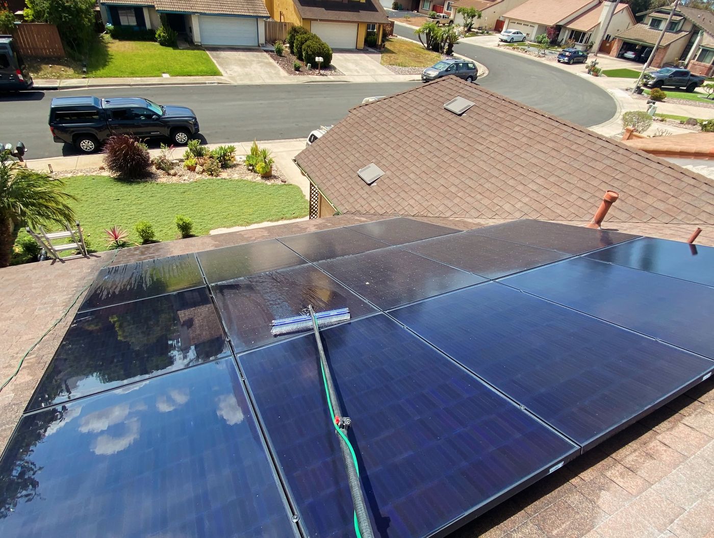 Cleaning a row of rooftop solar panels with a soft brush